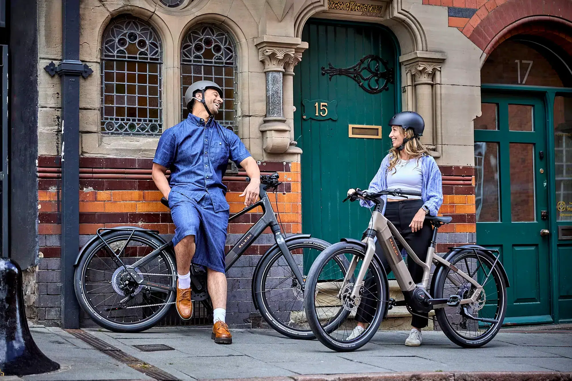 A man and a woman talking on the street next to their road legal Raleigh electric bikes.